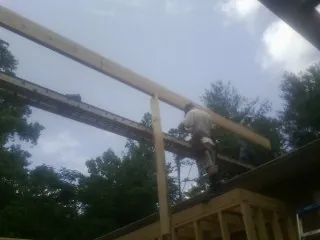 Carpenter setting a ridge beam over a new addition frame — Ice Dam Removal by Roofing Brothers in Gonzales