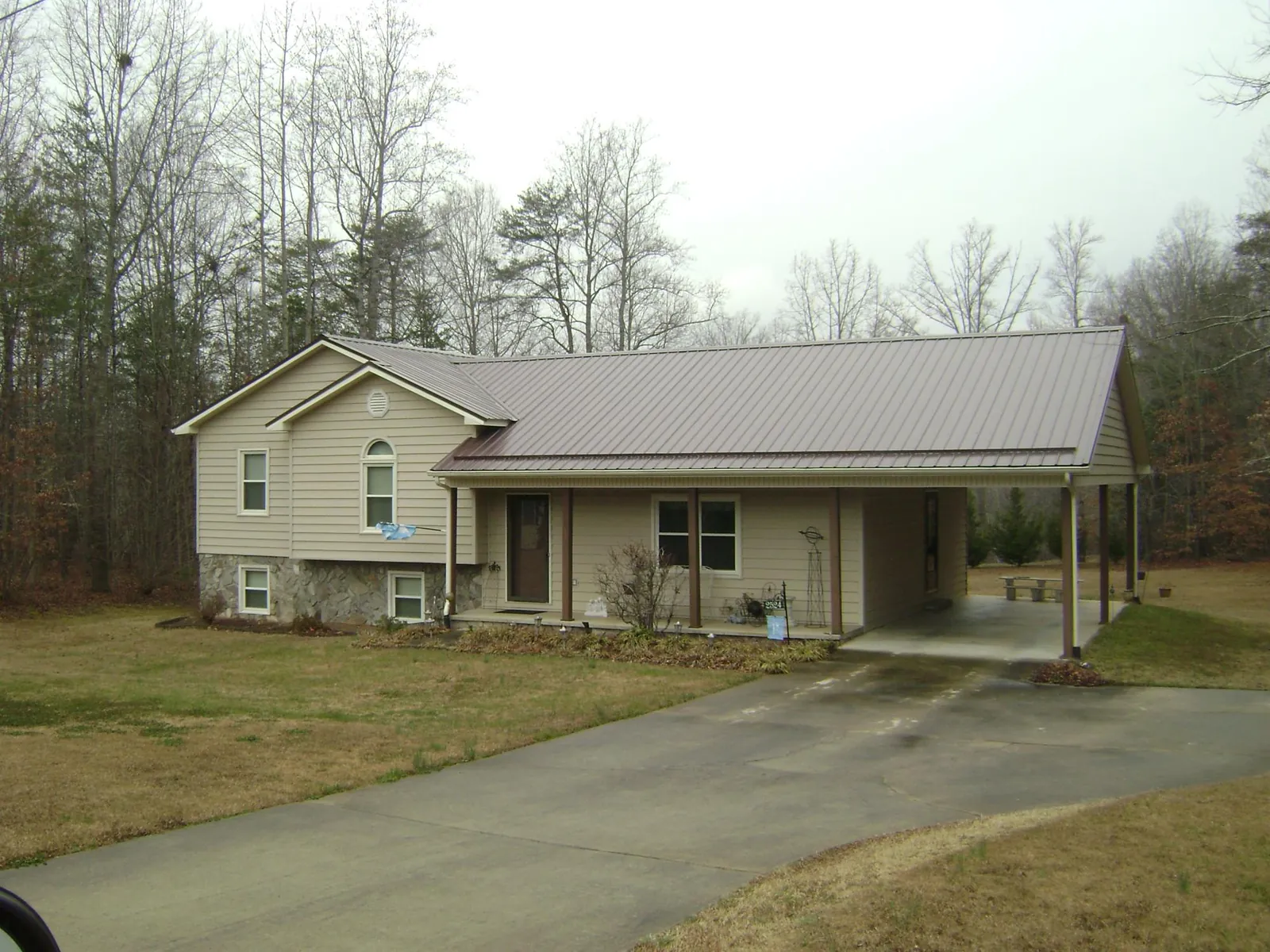 Brown metal roof on a tan split level home with an attached carport in Gonzales